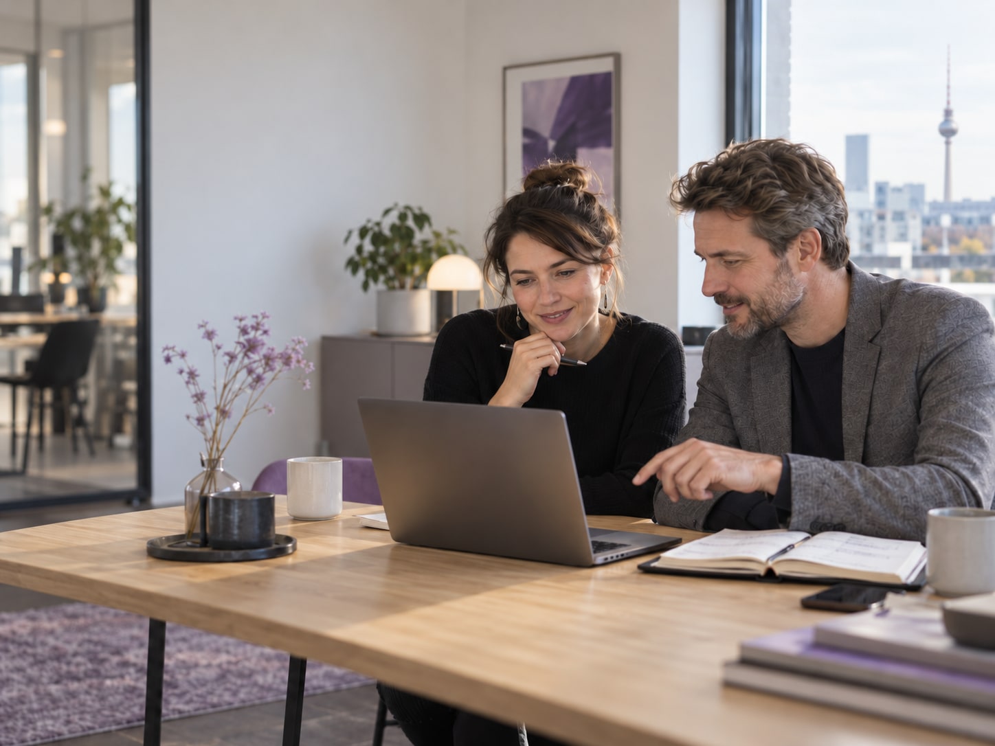 Zwei Personen besprechen am Laptop einen Lernplan in einem Berliner Büro.